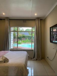 a bedroom with a bed and a window with a swimming pool at Eden homestay in Edenvale