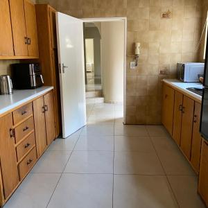 uma cozinha com armários de madeira e piso em azulejo branco em Eden homestay em Edenvale
