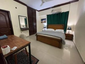 a bedroom with a bed and a table and green curtains at Backpackers Hostel Islamabad in Islamabad