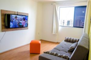 sala de estar con sofá y TV en la pared en Apartamento Beira Mar Maceió, en Maceió