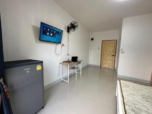 a room with a refrigerator and a tv on the wall at Flourish Homes ฟลอริชโฮมส์ ห้องพัก มอเกษตร สกลนคร in Ban Na Oi