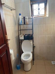 a bathroom with a toilet with a shelf above it at Calm Haven: Your Private Retreat in Kira