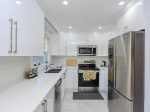 a kitchen with white cabinets and a stainless steel refrigerator at Elegant 5BDR in Mississauga, Brampton, Toronto in Mississauga