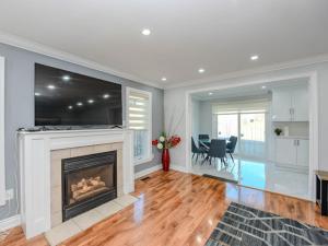 a living room with a fireplace with a large television at Elegant 5BDR in Mississauga, Brampton, Toronto in Mississauga