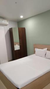 a bedroom with a large white bed with a mirror at The Lodge- Bed and Breakfast Hotel in Trivandrum
