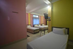 a small room with two beds and a table at HOTEL CKD in Gogāmukh
