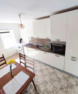 a kitchen with white cabinets and a wooden table and a table and chairs at Old House Lapis- pool, hot tub, BBQ in Zadvarje