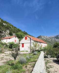 a white building with red windows on a mountain at Old House Lapis- pool, hot tub, BBQ in Zadvarje