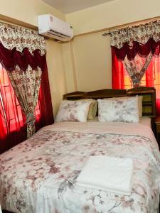 a bedroom with a large bed with red curtains at Destination Hope Booking in Georgetown