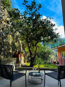 eine Terrasse mit 2 Stühlen, einem Tisch und einem Baum in der Unterkunft The Upper House in Riomaggiore