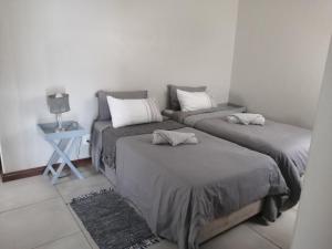a bedroom with two beds and a night stand with a lamp at 394OnEmus in Pretoria
