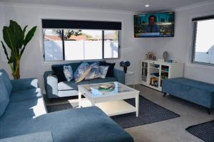 Una sala de estar con dos sofás azules y una mesa. en Pet Friendly Beach House with pool - Sleeps 10, en Urangan