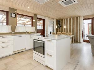 a kitchen with white cabinets and an island in it at 6 person holiday home in R dby in Rødby