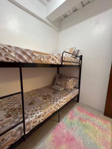 a bedroom with two bunk beds and a rug at Caishen Modern Affordable Apartelle 302 in Silang +5 photos