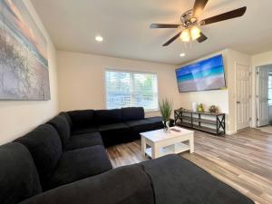a living room with a black couch and a ceiling fan at Beach House Cape May just 1 block from the Bay & a Short 5 minutes walk, Sleeps 19 in Cape May