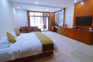 a bedroom with a large bed and a flat screen tv at Rainbow Valley Hot Spring Hotel in Gaizhou