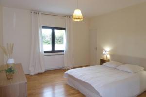 a bedroom with a white bed and a window at La Villa des Pins avec piscine et tennis in Garons