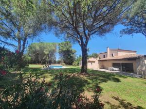 una casa con un patio con piscina y árboles en La Villa des Pins avec piscine et tennis en Garons