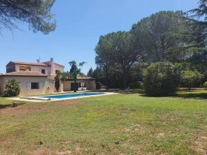 une grande cour avec une maison et une piscine dans l'établissement La Villa des Pins avec piscine et tennis, à Garons