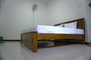a bedroom with a wooden bed with a fan at Golden Holiday Home in Arambegama