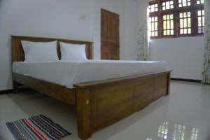 1 cama con marco de madera en un dormitorio en Golden Holiday Home, en Arambegama