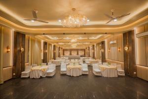 a banquet hall with white tables and a chandelier at Wood castle Spa & Resort in Rāmnagar