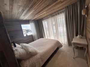 um quarto com uma cama, uma mesa e uma janela em Chalet Clémence em Taninges