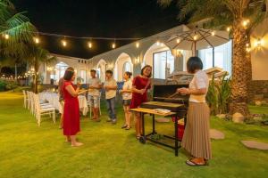 a group of people standing around a grill at a party at Amanda villa 4 Phan Thiết in Mui Ne