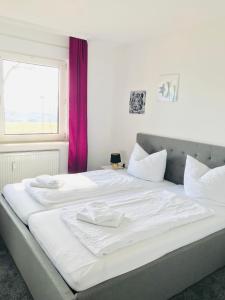 een groot wit bed met witte lakens en een raam bij Blockhäuser Fewo3 Harzblick in Braunlage