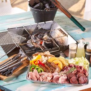 ein Teller mit Lebensmitteln auf einem Tisch mit Fleisch und Gemüse in der Unterkunft 海空リゾートうみのいえ in Yomitan