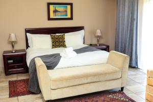 1 dormitorio con 1 cama y 1 silla en Thaba Legae Guest Lodge, en Rustenburg