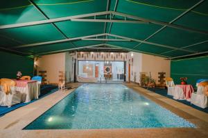 een groot zwembad met een groen plafond bij Thalir Resort in Alleppey
