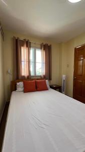 1 dormitorio con 1 cama blanca grande y ventana en Casa Leonardo, en Bacungan