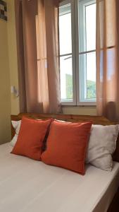 a bed with two orange pillows and two windows at Casa Leonardo in Bacungan
