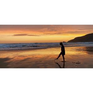 a man walking on the beach at sunset at MakiSaki Beach House in Herolds Bay