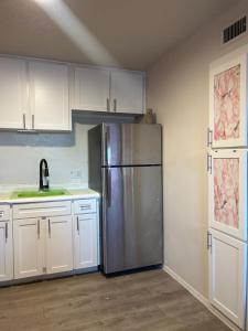una cocina con nevera de acero inoxidable y armarios blancos en Think Pink, en Fort Worth