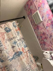 a bathroom with a shower with a fish themed shower curtain at Think Pink in Fort Worth
