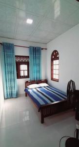1 dormitorio con 1 cama en una habitación con cortinas azules en Dream Villa Madiha Srilanka, en Matara