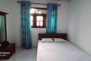 1 dormitorio con 1 cama con cortinas azules y ventana en Dream Villa Madiha Srilanka, en Matara