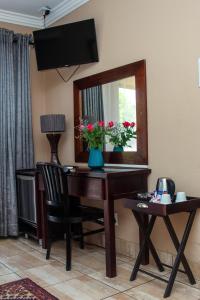 un escritorio con espejo y un jarrón de flores. en Thaba Legae Guest Lodge, en Rustenburg