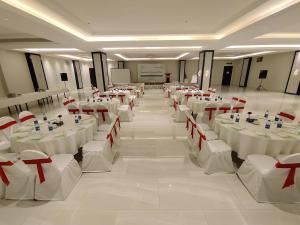 a banquet hall with white tables and red chairs at Ramada Hotel Gilgit in Gilgit
