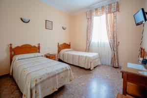 1 dormitorio con 2 camas y ventana en Hotel Chamizo, en El Arahal