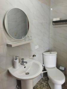 Baño blanco con aseo y lavamanos en Casa Leonardo, en Bacungan