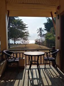 - une table et des chaises sur une terrasse couverte offrant une vue sur l'océan dans l'établissement Chaithalay Khanom Resort, à Ban Phang Phrao