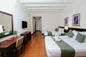 The Suites At Mount Malarayat في ليبا: غرفة فندقية بسريرين ومكتب