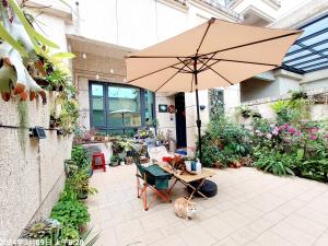 a patio with an umbrella and a cat sitting under it at 一宿來民宿 in Fengping