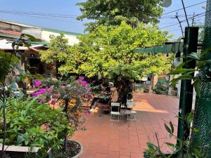 a garden with trees and chairs and flowers at Cọ cùn homestay/ Handmade/ Artwork (2 beds) in Buon Ma Thuot