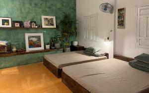 two beds in a room with green walls at Cọ cùn homestay/ Handmade/ Artwork (2 beds) in Buon Ma Thuot