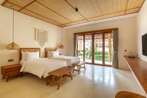 two beds in a room with a tv and a couch at Bingin Sebelas in Uluwatu