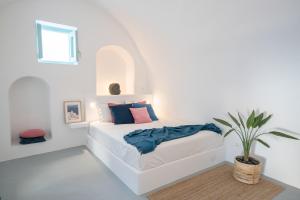 una camera bianca con un letto con una pianta in vaso di Vima Santorini, Traditional Luxury a Emporio
